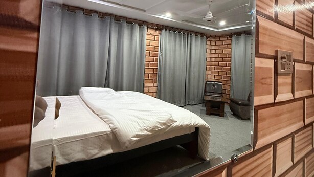 A bedroom with a large mirror, a bed, a wooden wall panel, and a ceiling fan. - Spacious 9-bedroom hotel suites in beautiful Skardu with WiFi (Skardu)