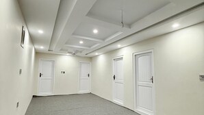 A corridor with four white doors, a ceiling fan, recessed lighting, and a patterned carpet. - Spacious 9-bedroom hotel suites in beautiful Skardu with WiFi (Skardu)