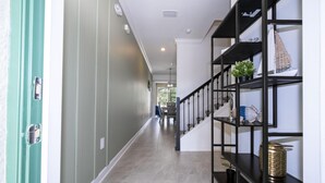 A hallway with a staircase, a green door, and a black shelving unit with decorative items. - Storey Lake Resort, Private Pool, Near Famous Attractions!! (Kissimmee)