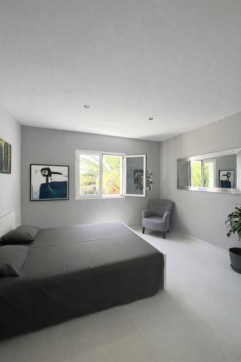 A modern bedroom with a large bed, a chair, and artwork on the walls.