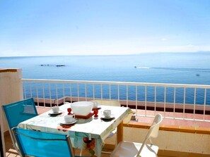 En balkon med et spisebord, der vender ud mod et roligt hav med både.