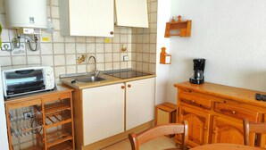 Una cocina compacta con microondas, lavamanos y armarios de madera.