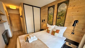 A bedroom with a wooden wall, a bed with white bedding, and a painting of a landscape.