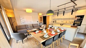 A modern apartment with a dining area, kitchen, and living space.