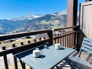 Un balcone con tavolo e sedie, affacciato su un paesaggio montuoso.