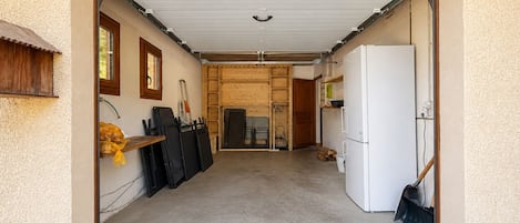 Een garage met een witte koelkast, een houten deur en een betonnen vloer.