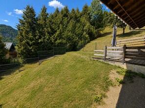 A grassy slope with a wooden bench and a fence.
