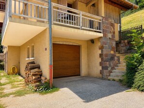 Un edificio a due piani con un balcone in legno, un portone di garage e una scalinata in pietra.