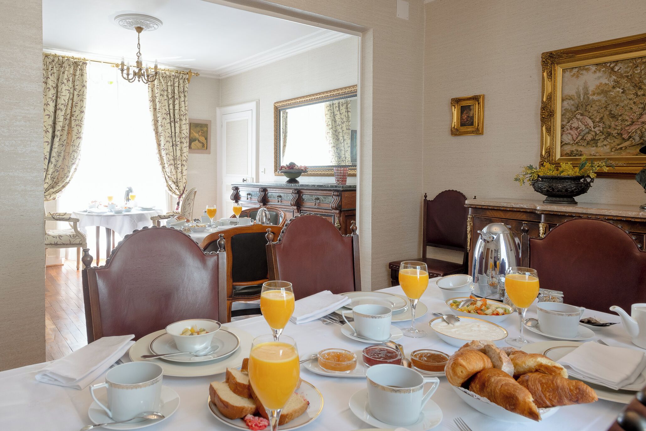 Une table mise pour le petit-déjeuner, avec une place pour deux personnes, comprenant des croissants, du jus d’orange et divers autres éléments pour le petit-déjeuner.