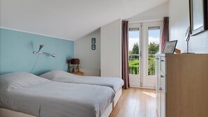 Una camera da letto con due letti, una scrivania, una sedia e una finestra con tende.
