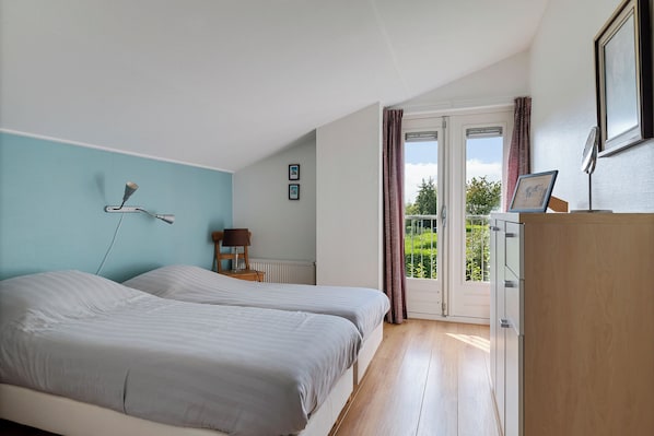 A bedroom with two beds, a desk, a chair, and a window with curtains.