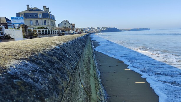 Ein Küstenhotel mit einer Steinsichtmauer, einem Strand und freiem Blick auf das Meer.