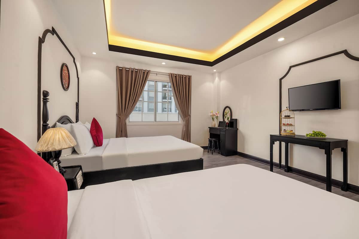 Une chambre d’hôtel avec deux lits, un bureau, une télévision et une fenêtre avec des rideaux.