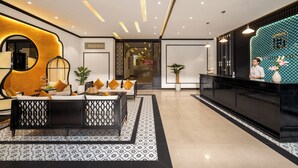 Un hall d’hôtel moderne comprenant un comptoir d’accueil, un espace salon et des éléments décoratifs.