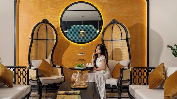 Une pièce comprenant un canapé, deux fauteuils, une table basse et un mur décoratif orné d’un miroir rond.