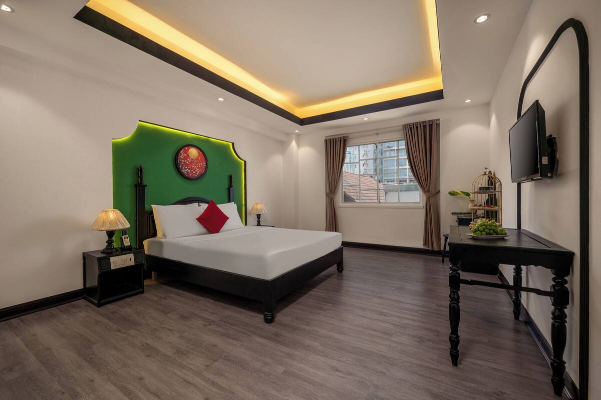 Une chambre d’hôtel moderne équipée d’un lit, de tables de chevet, d’une télévision et d’une fenêtre avec des rideaux.