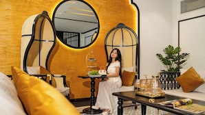 Un intérieur moderne avec un canapé, un miroir rond, une petite table sur laquelle se trouve un plateau de fruits et une plante en pot.
