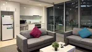 Una sala de estar moderna con sofás grises, una mesa de centro blanca y vistas de la ciudad a través de amplios ventanales.