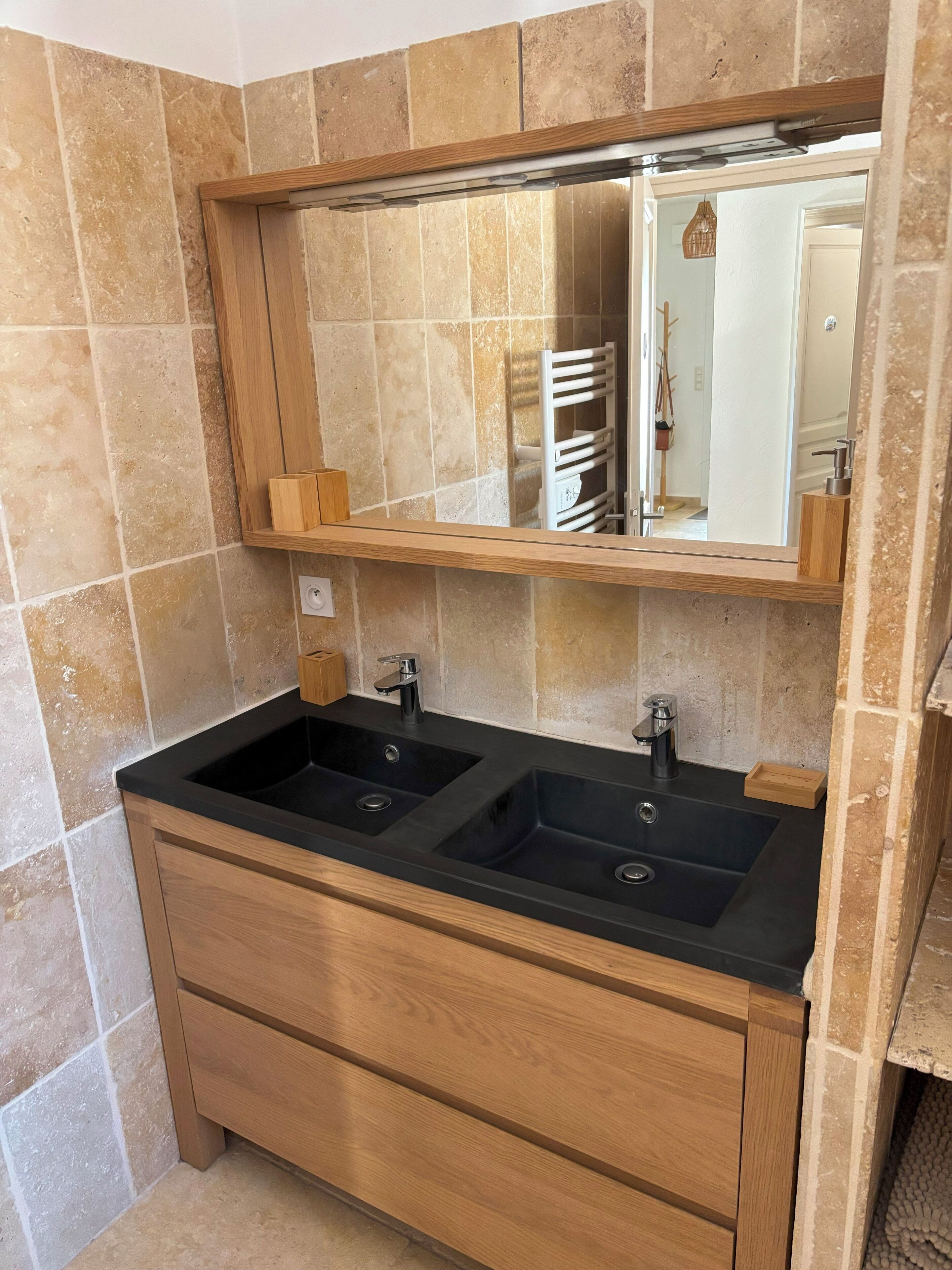 A bathroom with two black sinks, a wooden vanity, and a mirror above the sink.