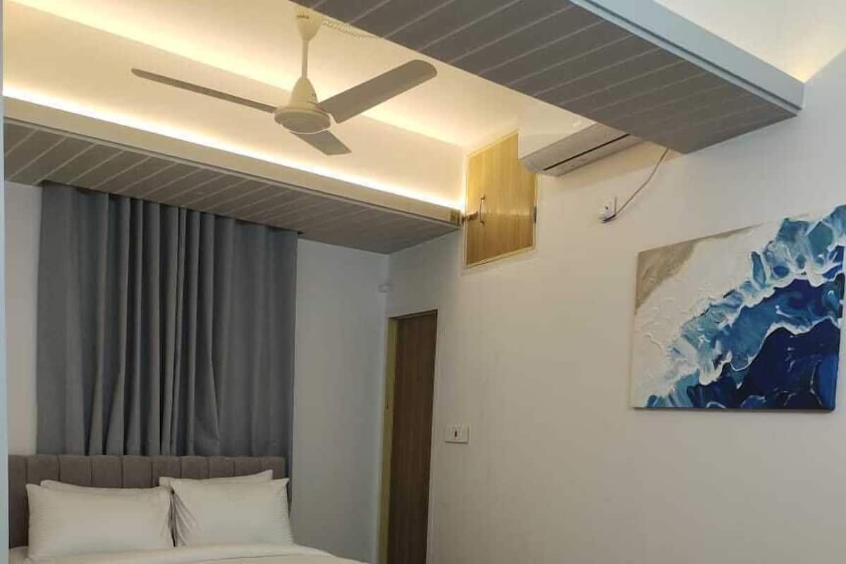 A modern bedroom with a bed, ceiling fan, and artwork on the wall.