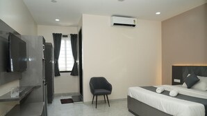 A modern hotel room with a bed, a chair, a TV, and a small desk. - Hotel Royal Stay inn (Patancheruvu)