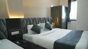 A hotel room with a large bed, a bedside table with a phone and remote, a wardrobe, and a window with curtains. - Hotel Royal Stay inn (Patancheruvu)