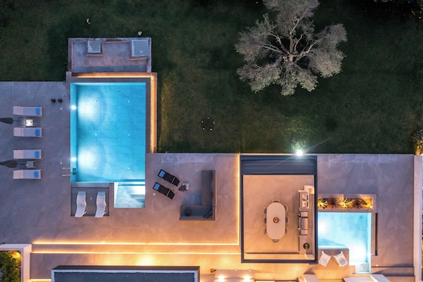 Un espace de vie extérieur moderne comprenant une piscine, des sièges et un coin repas.