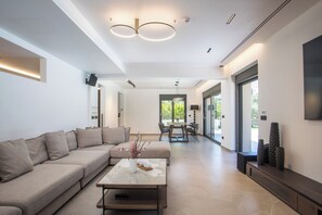 Una sala de estar moderna con un sofá modular, una mesa de centro y un comedor al fondo.
