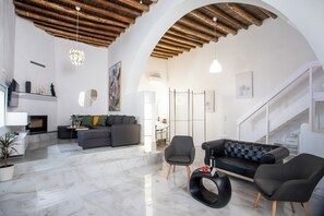 A spacious living area with a high ceiling, a fireplace, and a staircase leading to an upper level.