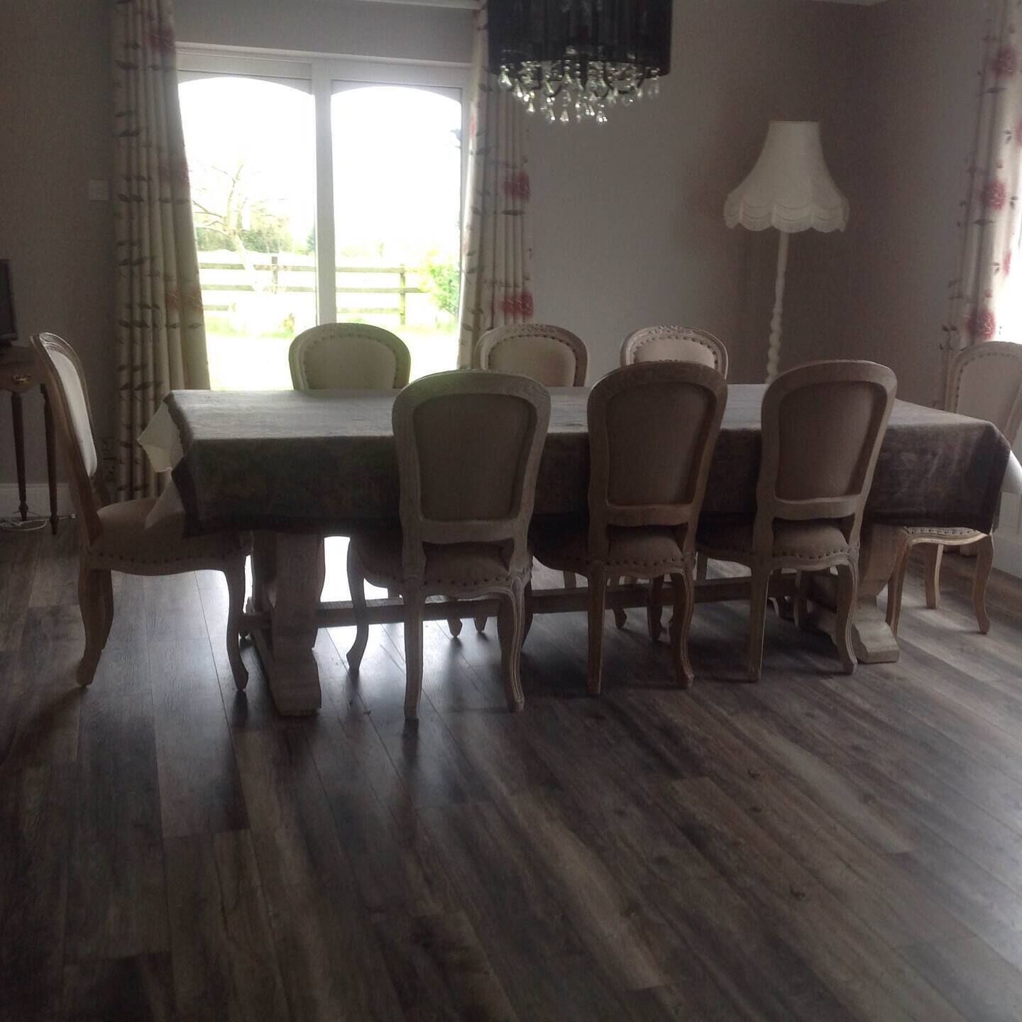 Un coin repas avec une table et des chaises en bois, un lustre et une vue par la fenêtre.