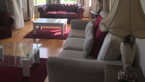 Ein Wohnzimmer mit Sofa, Sessel, Couchtisch und Lampe.