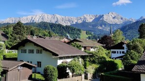 A mountain village with traditional houses, a church, and a clear view of the mountains. - AlpenHorizont: Spacious vacation apartment with a dream view for families & friends (Garmisch-Partenkirchen)