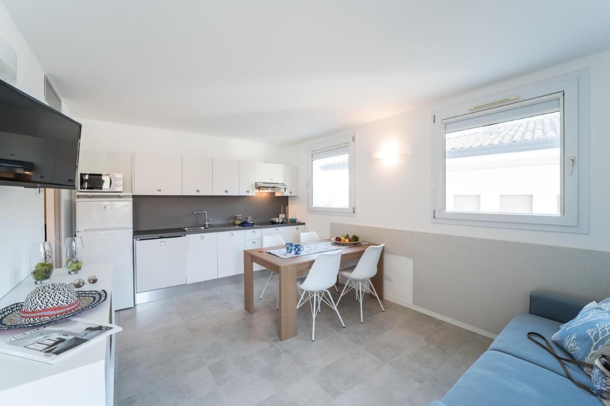 Una cocina compacta con armarios blancos, microondas y un comedor con mesa y sillas.