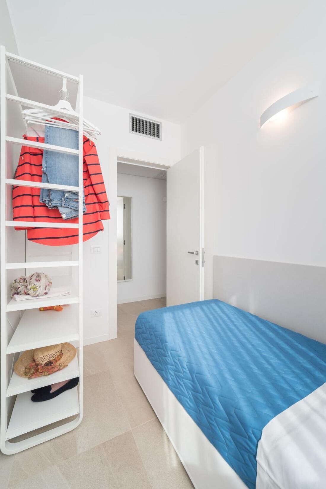 Une chambre à coucher comprenant un lit, une armoire et une porte donnant sur une autre pièce.