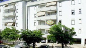 A multi-story white building with balconies and a central entrance.