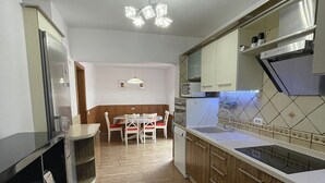 Eine moderne Küche mit Essbereich, ausgestattet mit einer zentralen Kochinsel, Holzschränken und einer gefliesten Rückwand.