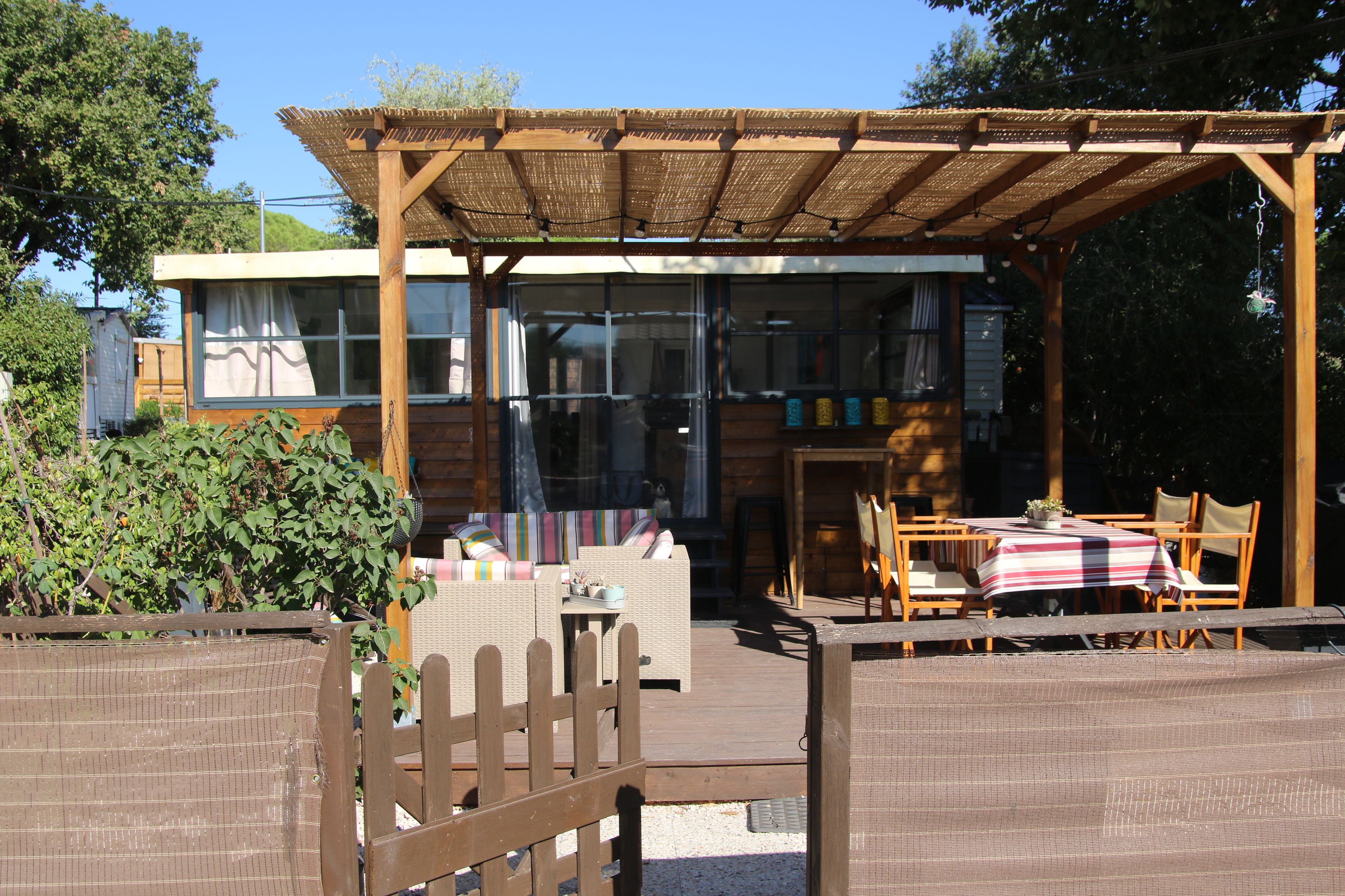 Ein überdachter Außenbereich mit Holzmöbeln und einer Pergola.