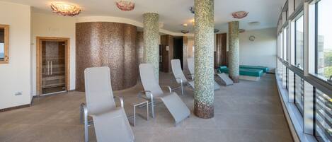 A modern waiting area with a row of chairs, a reception desk, and a large window offering a view.