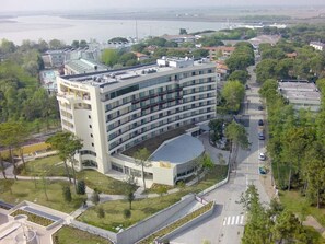 Ein modernes Hotel mit geschwungener Fassade, mehreren Etagen und einer Dachterrasse.