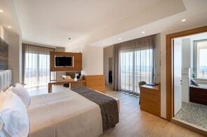 Ein modernes Hotelzimmer mit einem großen Bett, einem Schreibtisch, einem Fernseher und einem Balkon mit Blick.