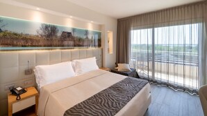 Ein modernes Hotelzimmer mit einem großen Bett, einem Schreibtisch und Blick auf eine Landschaft durch das Fenster.