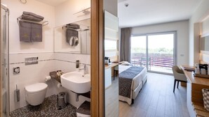 Ein modernes Hotelzimmer mit Bad, Balkon und Schreibtisch.