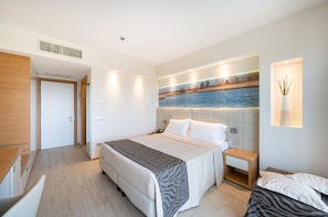 A modern hotel room with a large bed, a bedside table, a nightstand, and a wall-mounted lamp.