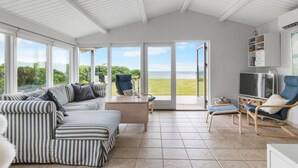 Una habitación amplia con un gran ventanal, un sofá, un televisor y una estantería.