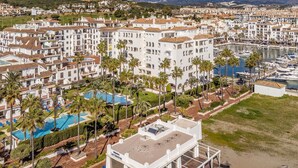 A coastal hotel with multiple white buildings, a marina, and a pool area with palm trees.