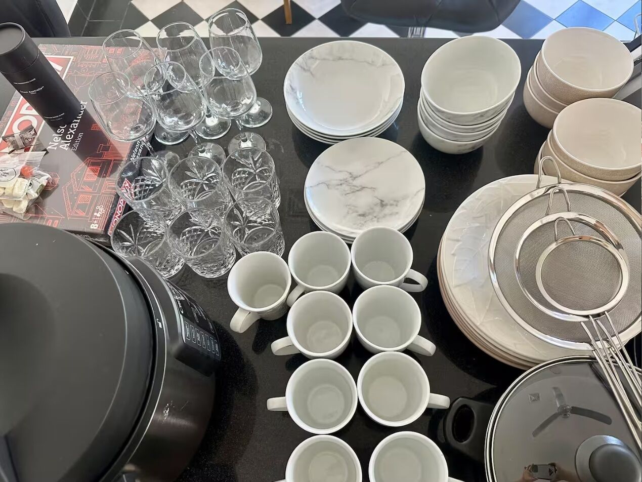 Un tavolo con vari utensili da cucina, tra cui piatti, tazze e un colino.