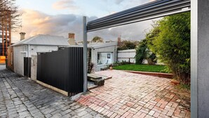 Een woonhuis met een verharde oprit, een omheinde tuin en een modern metalen hek.