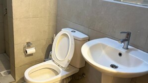 A bathroom with a toilet, a sink, and a shower area. - Martin Aviator Apartement (Kigali)
