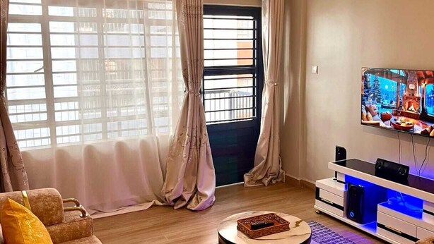 A living room with a sofa, a coffee table, a TV, and a speaker. - Martin Aviator Apartement (Kigali)