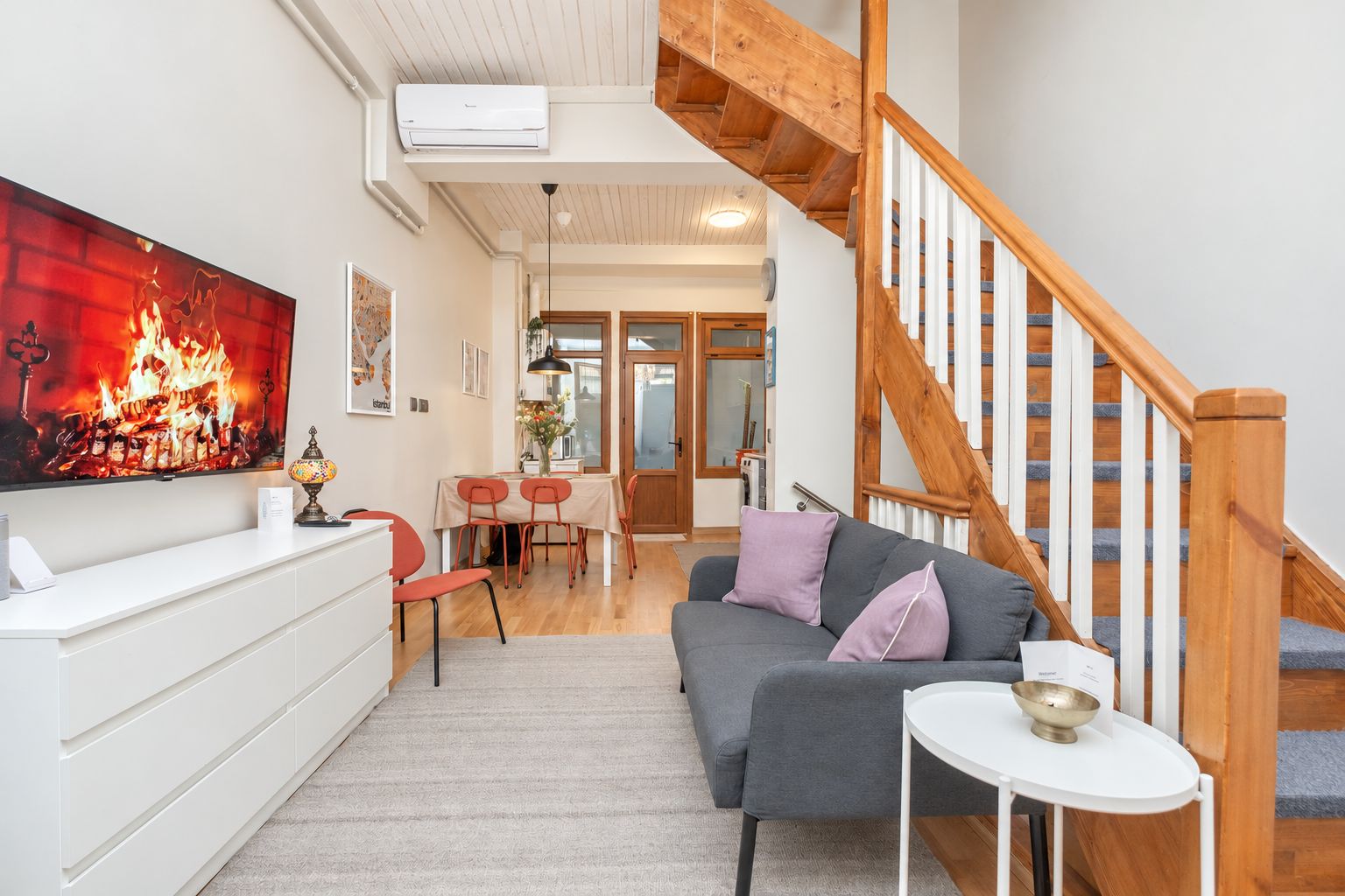 Un salon moderne avec un canapé gris, une table basse blanche et un escalier en bois.